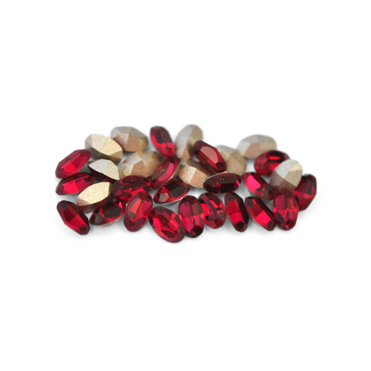 Oval shaped faceted Austrian crystal rhinestones in the color Ruby displayed on a white background. 