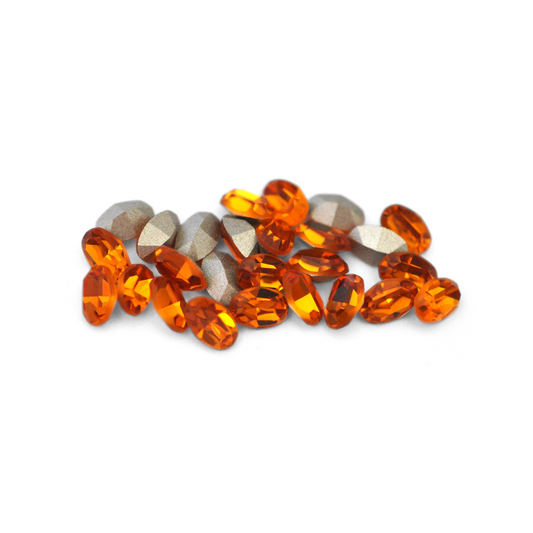 Oval shaped faceted Austrian crystal rhinestones in the color Topaz displayed on a white background. 
