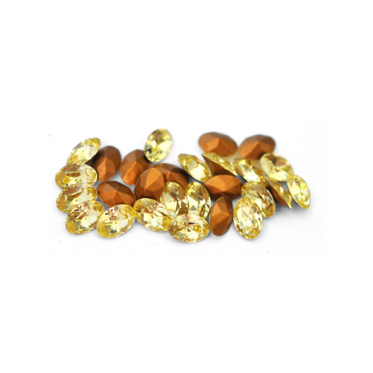 Oval shaped faceted Austrian crystal rhinestones in the color Jonquil displayed on a white background. 