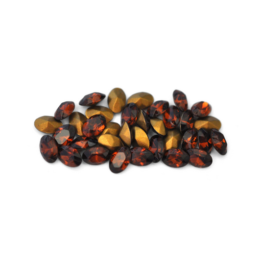 Oval shaped faceted Austrian crystal rhinestones in the color Smoked Topaz displayed on a white background. 