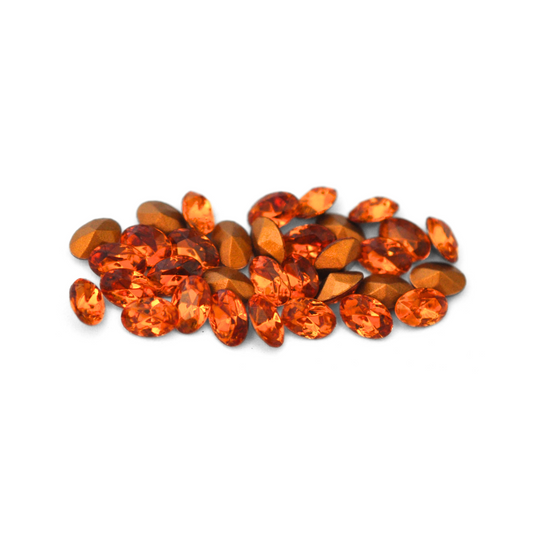 Oval shaped faceted Austrian crystal rhinestones in the color Topaz displayed on a white background. 