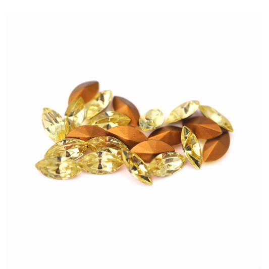 Navette shaped faceted Austrian crystal rhinestones in the color Jonquil displayed on a white background. 