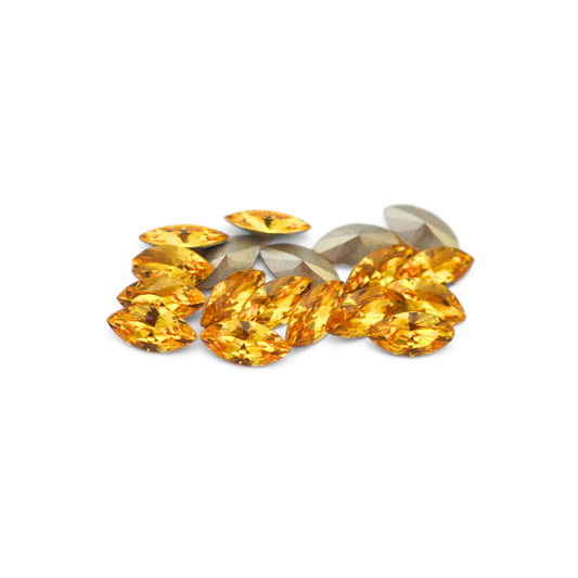 Navette shaped faceted Austrian crystal rhinestones in the color Light Topaz displayed on a white background.