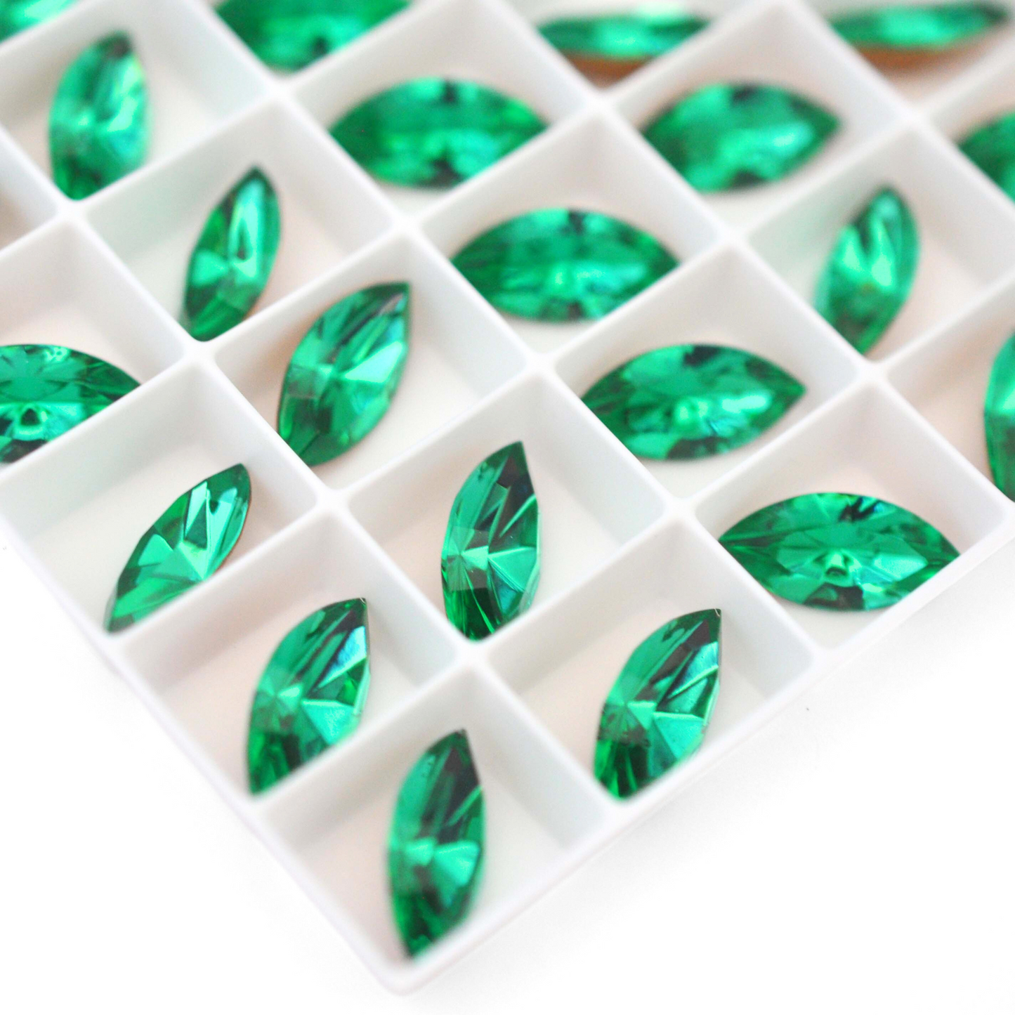 Navette shaped faceted Austrian crystal rhinestones in the color Light Emerald displayed on a white background.