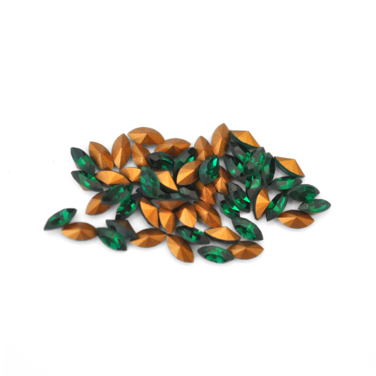 Navette shaped faceted Austrian crystal rhinestones in the color Emerald displayed on a white background.