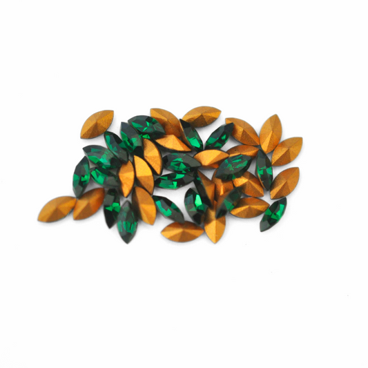 Navette shaped faceted Austrian crystal rhinestones in the color Emerald displayed on a white background.