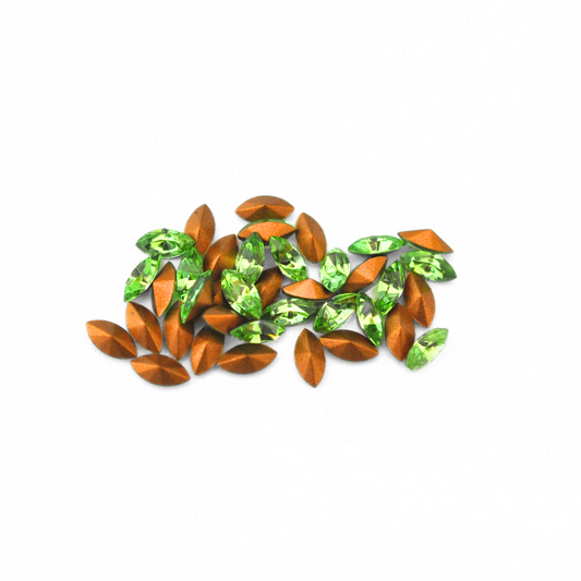 Navette shaped faceted Austrian crystal rhinestones in the color Peridot displayed on a white background.