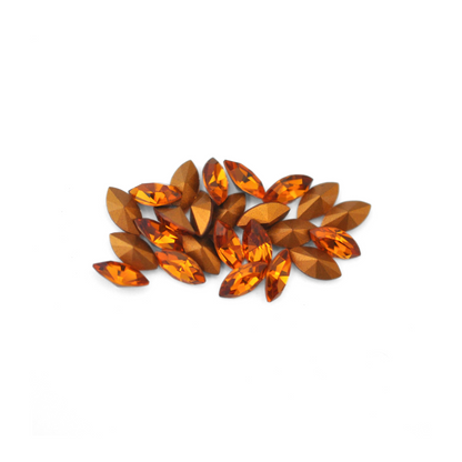 Navette shaped faceted Austrian crystal rhinestones in the color Topaz displayed on a white background.