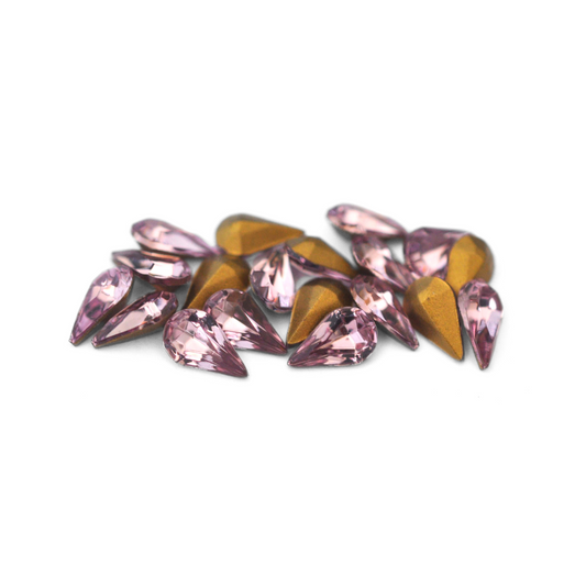 Pear shaped faceted Austrian crystal rhinestones in the color Light Amethyst displayed on a white background. 
