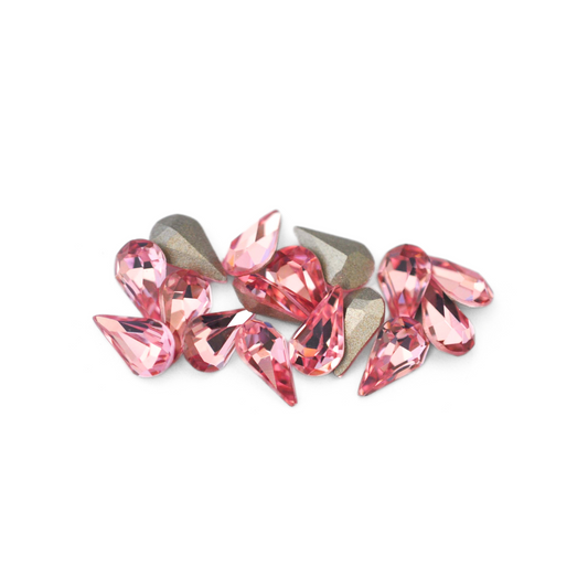 Pear shaped faceted Austrian crystal rhinestones in the color Light Rose displayed on a white background. 