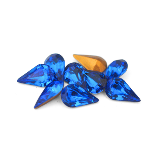 Pear shaped faceted Austrian crystal rhinestones in the color Capri Blue displayed on a white background. 