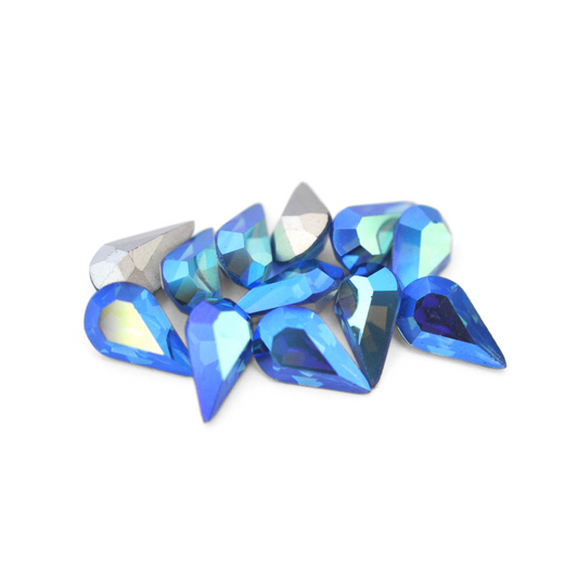 Pear shaped faceted Austrian crystal rhinestones in the color Sapphire AB displayed on a white background. 