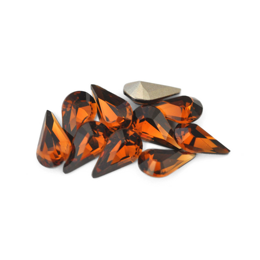 Pear shaped faceted Austrian crystal rhinestones in the color Smoked Topaz displayed on a white background. 