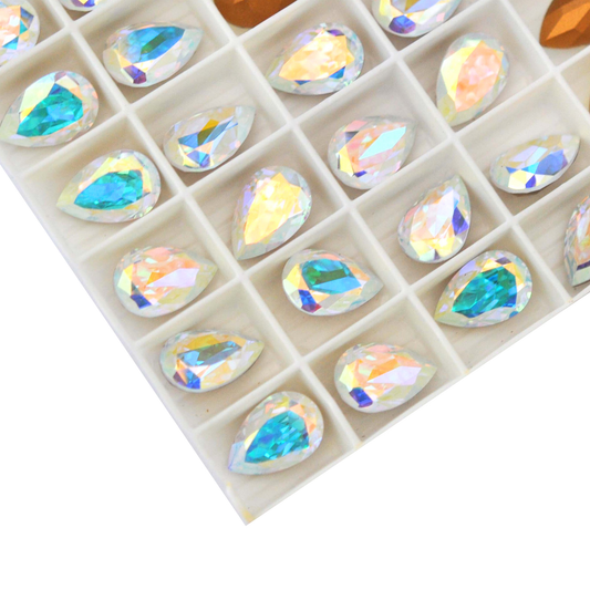 Pear shaped faceted Austrian crystal rhinestones in the color Crystal AB displayed in the packaging tray on a white background. 