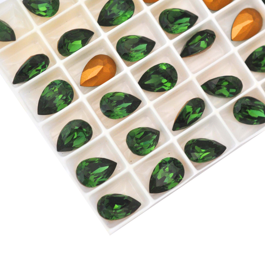 Pear shaped faceted Austrian crystal rhinestones in the color Green Turmaline displayed in the packaging tray on a white background. 