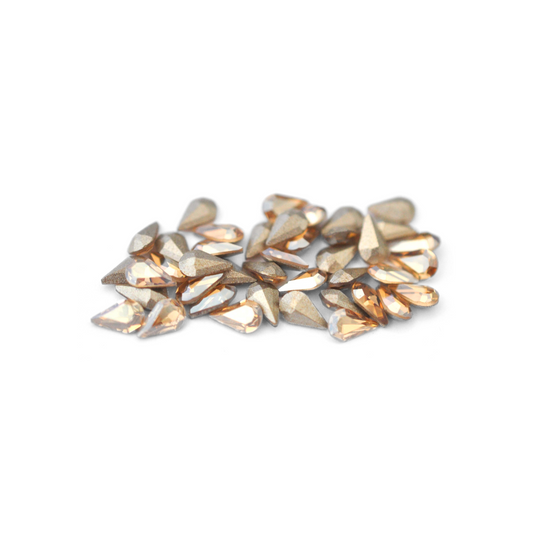 Pear shaped faceted Austrian crystal rhinestones in the color Golden Shadow displayed on a white background. 