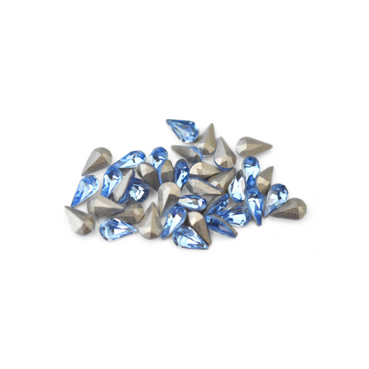 Pear shaped faceted Austrian crystal rhinestones in the color Light Sapphire displayed on a white background. 