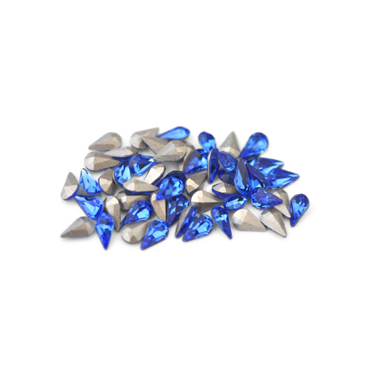 Pear shaped faceted Austrian crystal rhinestones in the color Sapphire displayed on a white background. 