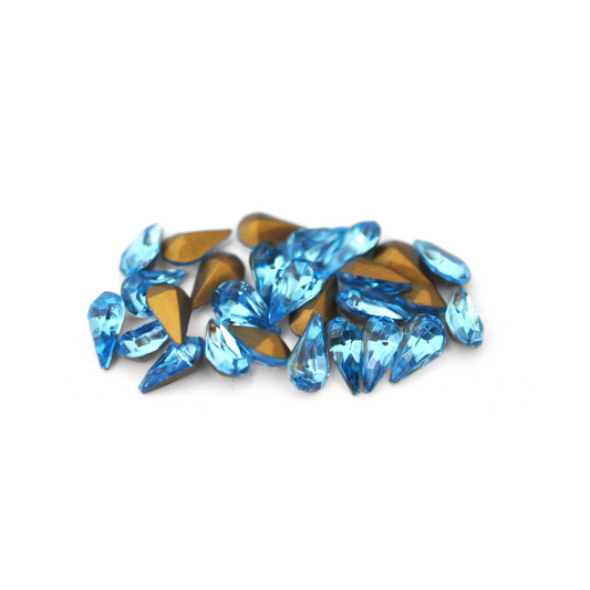 Pear shaped faceted Austrian crystal rhinestones in the color Aquamarine displayed on a white background. 