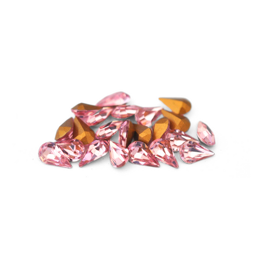 Pear shaped faceted Austrian crystal rhinestones in the color Light Rose displayed on a white background. 