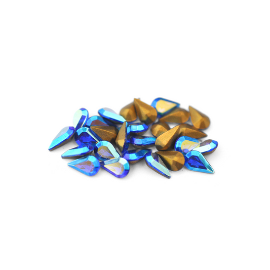 Pear shaped faceted Austrian crystal rhinestones in the color Sapphire AB displayed on a white background. 