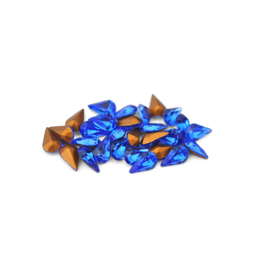 Pear shaped faceted Austrian crystal rhinestones in the color Sapphire displayed on a white background. 
