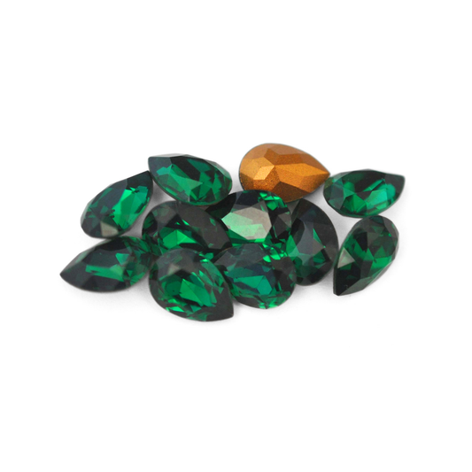 Pear shaped faceted Austrian crystal rhinestones in the color Emerald displayed on a white background. 