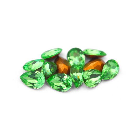 Pear shaped faceted Austrian crystal rhinestones in the color Peridot displayed on a white background. 
