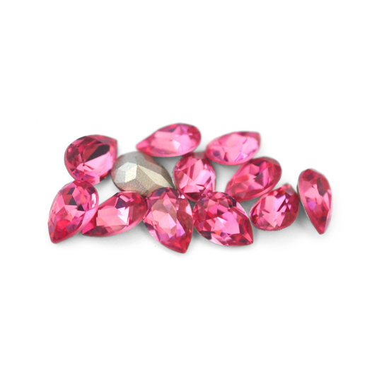 Pear shaped faceted Austrian crystal rhinestones in the color Rose displayed on a white background. 