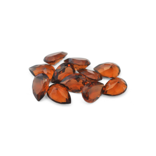 Pear shaped faceted Austrian crystal rhinestones in the color Smoked Topaz Unfoiled displayed on a white background. 