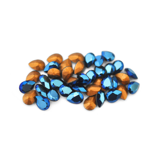 Pear shaped faceted Austrian crystal rhinestones in the color Metallic Blue displayed on a white background. 