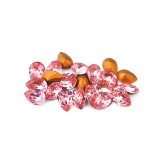 Pear shaped faceted Austrian crystal rhinestones in the color Light Rose displayed on a white background. 