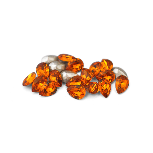 Pear shaped faceted Austrian crystal rhinestones in the color Topaz displayed on a white background. 