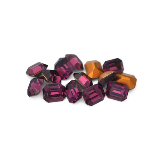 Octagon shaped faceted Austrian crystal rhinestones in the color Amethyst displayed on a white background. 