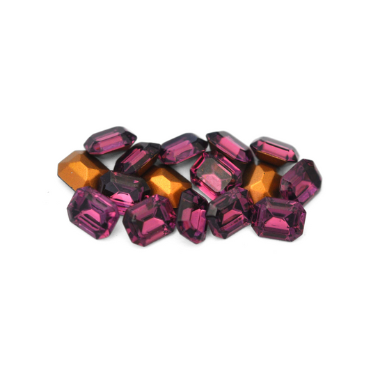 Octagon shaped faceted Austrian crystal rhinestones in the color Amethyst displayed on a white background. 