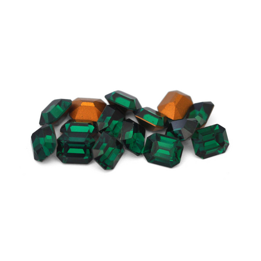 Octagon shaped faceted Austrian crystal rhinestones in the color Emerald displayed on a white background. 