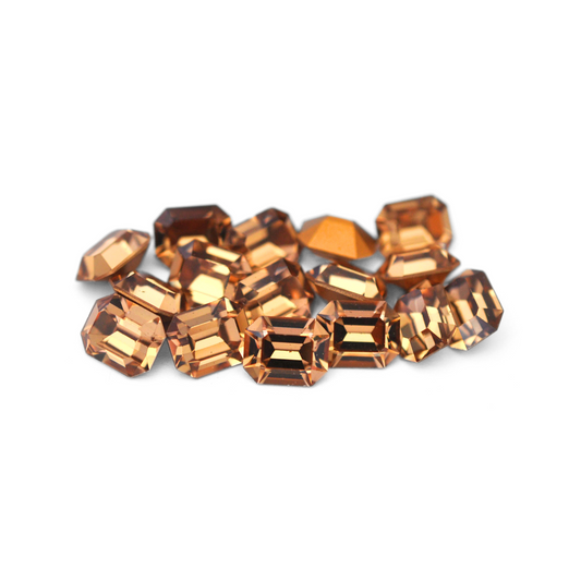 Octagon shaped faceted Austrian crystal rhinestones in the color Light Colorado Topaz displayed on a white background. 