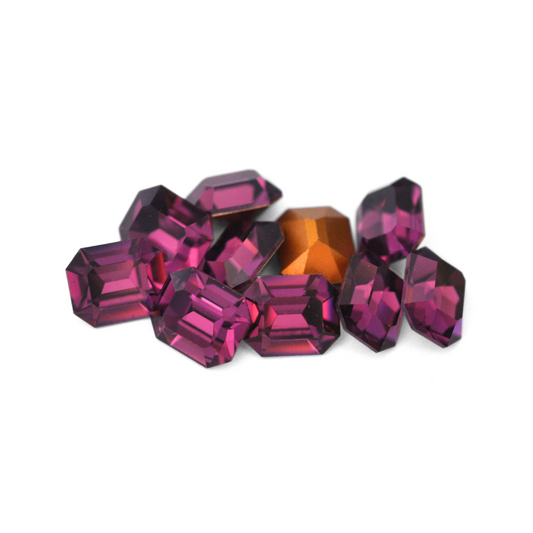 Octagon shaped faceted Austrian crystal rhinestones in the color Amethyst displayed on a white background. 