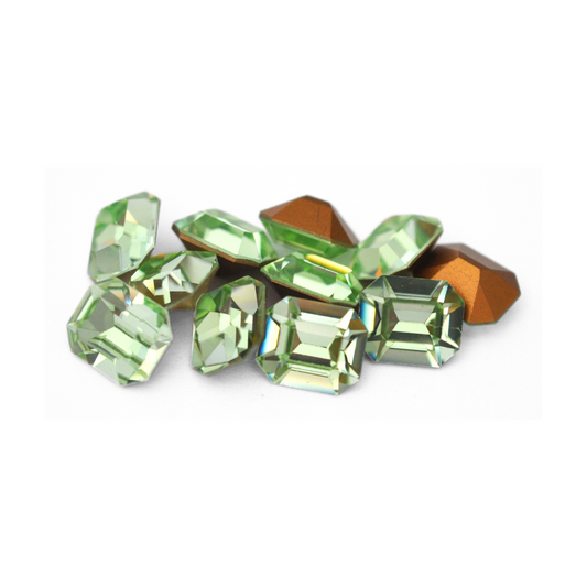 Octagon shaped faceted Austrian crystal rhinestones in the color Chrysolite displayed on a white background. 