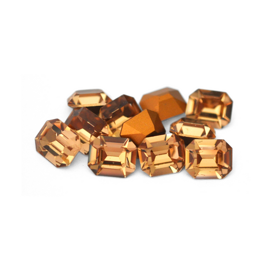 Octagon shaped faceted Austrian crystal rhinestones in the color Light Colorado Topaz displayed on a white background. 
