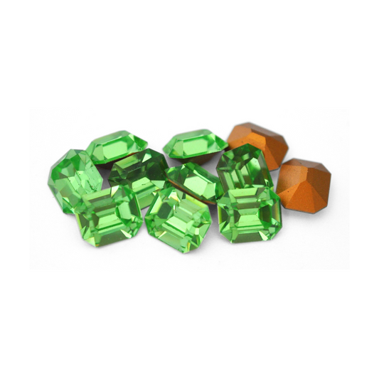 Octagon shaped faceted Austrian crystal rhinestones in the color Peridot displayed on a white background. 