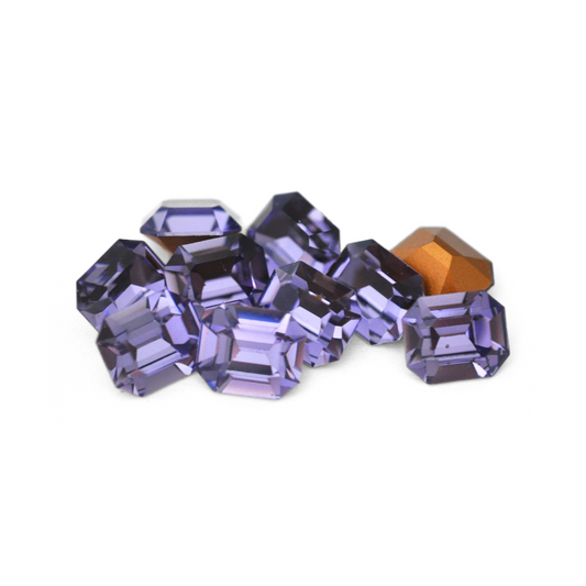 Octagon shaped faceted Austrian crystal rhinestones in the color Tanzanite displayed on a white background. 