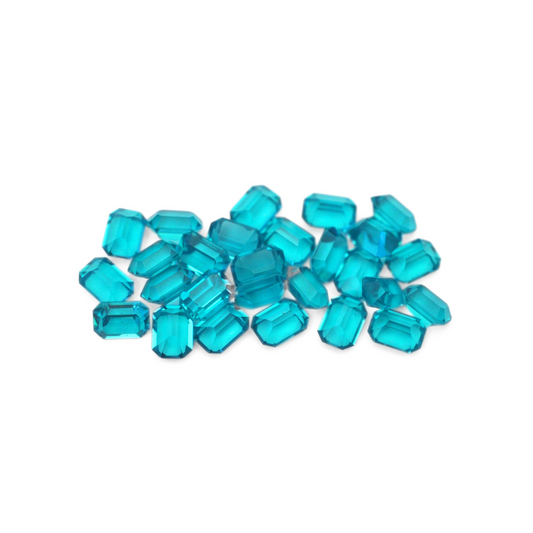 Octagon shaped faceted Austrian crystal rhinestones in the color Blue Zircon displayed on a white background. 