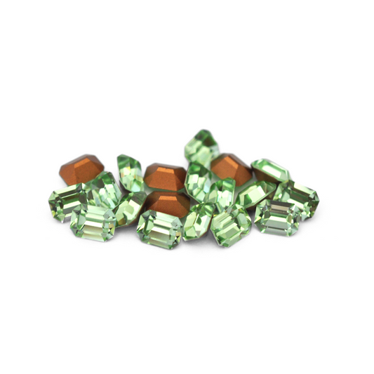 Octagon shaped faceted Austrian crystal rhinestones in the color Chrysolite displayed on a white background. 