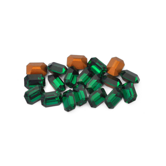 Octagon shaped faceted Austrian crystal rhinestones in the color Emerald displayed on a white background. 
