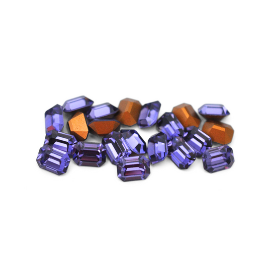 Octagon shaped faceted Austrian crystal rhinestones in the color Tanzanite displayed on a white background. 