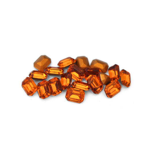 Octagon shaped faceted Austrian crystal rhinestones in the color Topaz displayed on a white background. 