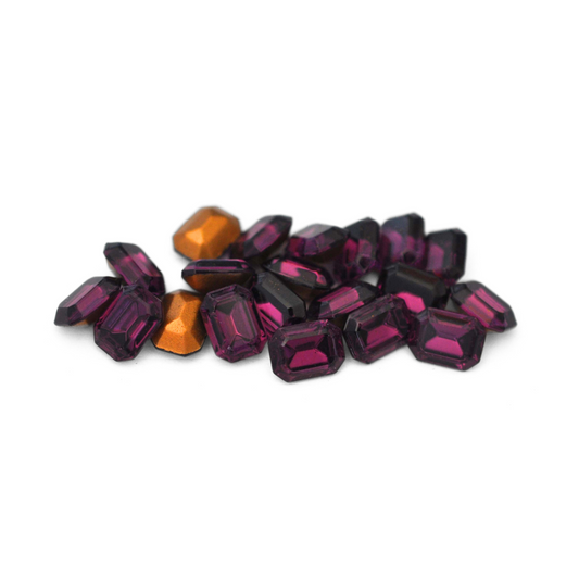 Octagon shaped faceted Austrian crystal rhinestones in the color Amethyst displayed on a white background. 