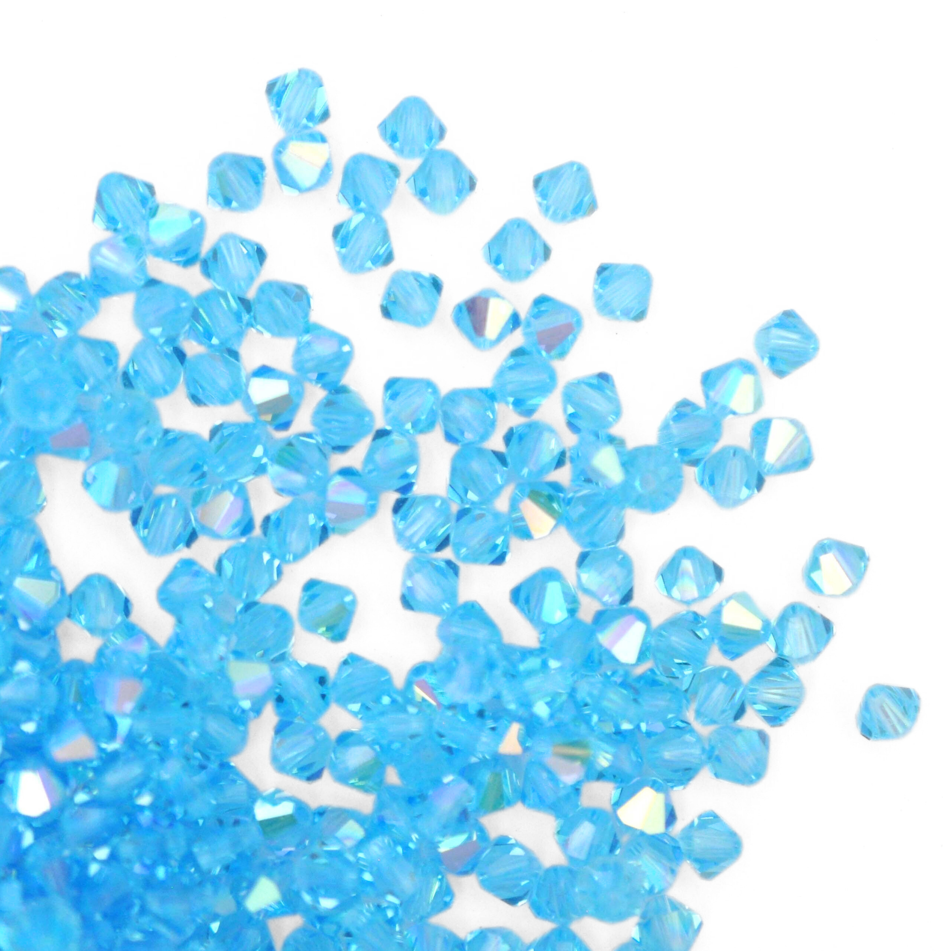 Austrian crystal 5328 bicone beads in the color Aquamarine AB spilling out onto a white background. 