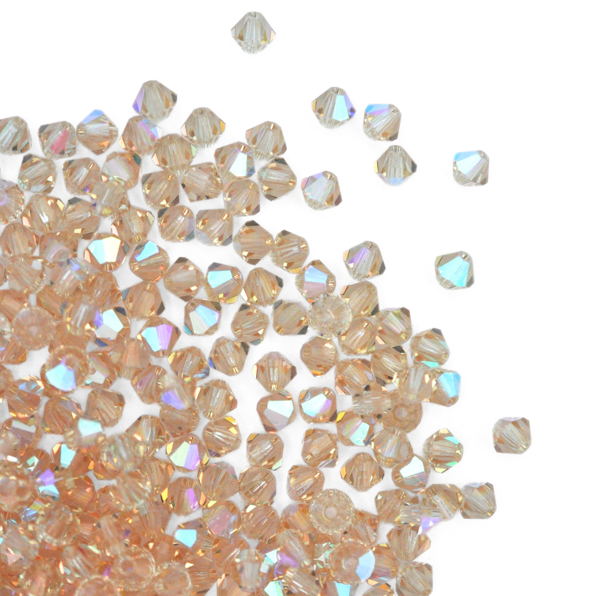 Austrian crystal 5328 bicone beads in the color Cantaloupe AB spilling out onto a white background. 